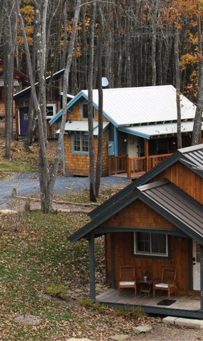 Several of Blue Moon Rising's hand-built cabins stepping down a wooded hillside along the gravel lane